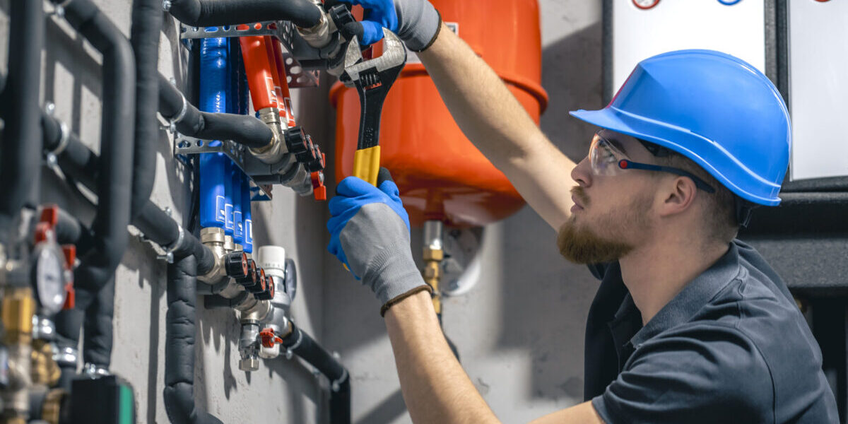 man-installs-heating-system-house-checks-pipes-with-wrench man-installs-heating-system-house-checks-pipes-with-wrench